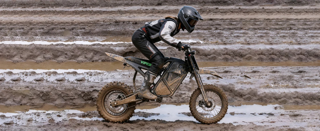Electric dirt bike ridden on a dirt track, knobby tires and front suspension