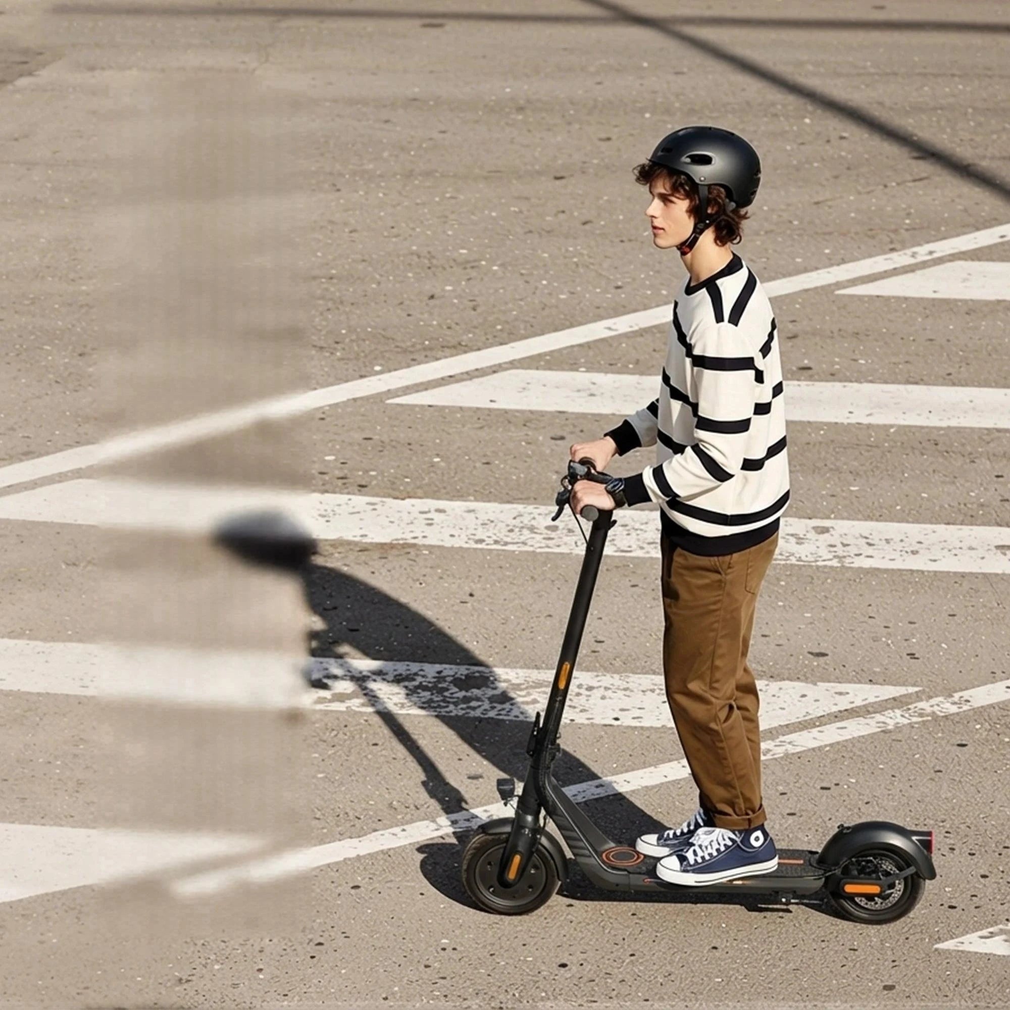 Rider on an electric scooter wearing a helmet and striped sweater