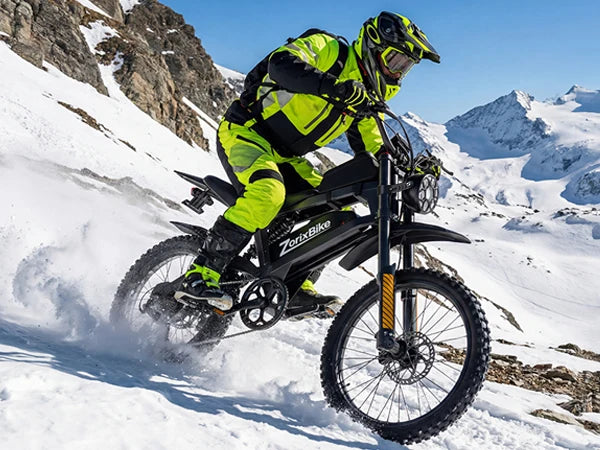 Neon green rider on black electric dirt bike on snow with knobby tires